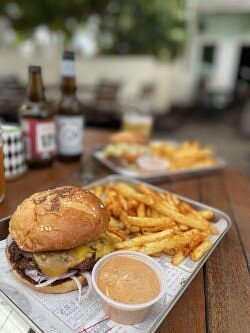 Smashed cheeseburger with fries and dipping sauce on a metal tray at BRGR HAUS