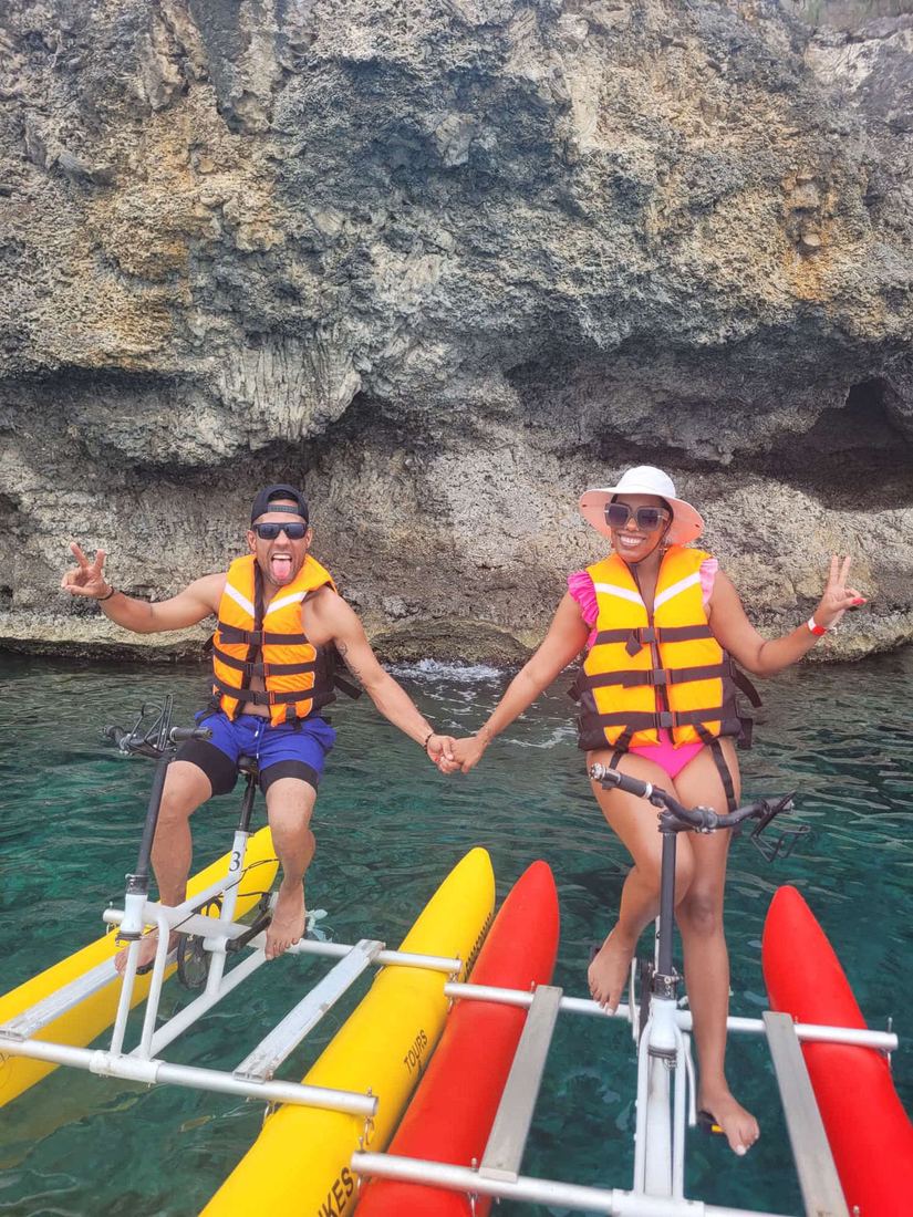 Pareja riendo en bicicletas acuáticas cerca de la cueva marina, Curazao